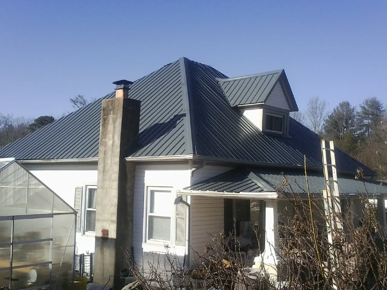 Dark blue standing seam metal roof on a white farmhouse with dormer — Slate & Tile Roof Repair by Roofing Brothers in Oak Lawn