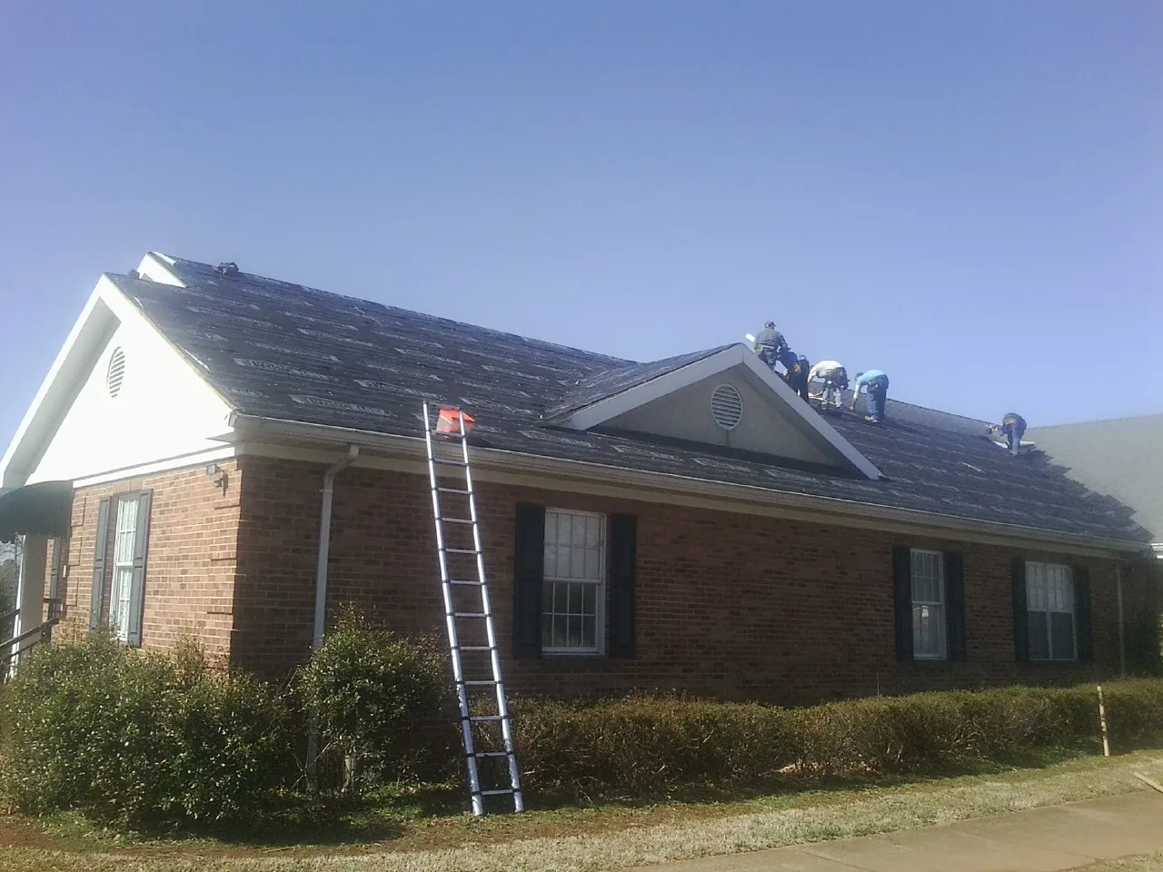 Crew tearing shingles off a brick ranch roof with a ladder set — Metal Roof Repair work by our crew in Oak Lawn