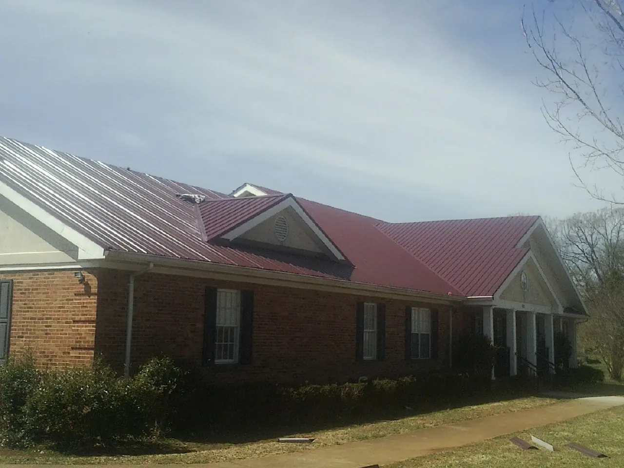 Red metal roof with gabled entries on a long brick building, from a Hail Damage Roof Repair job in Oak Lawn