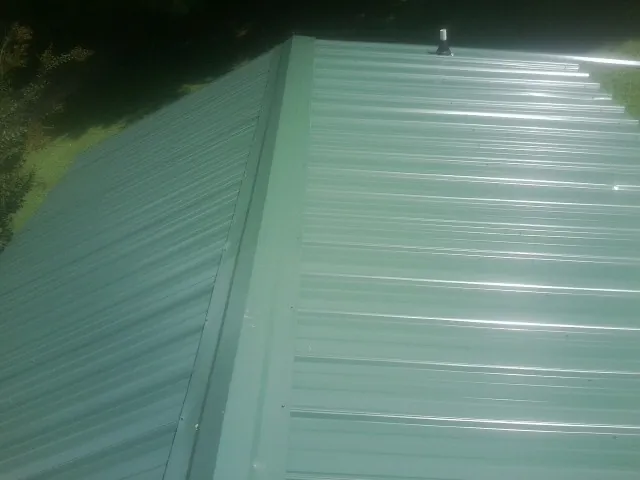 New green metal panels meeting at the ridge of a roof — Flat Roof Repair work by our crew in Oak Lawn
