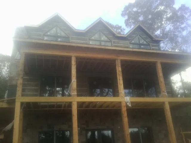 Dormers and porch framing on a large log home under construction — Roof Coating work by our crew in Oak Lawn