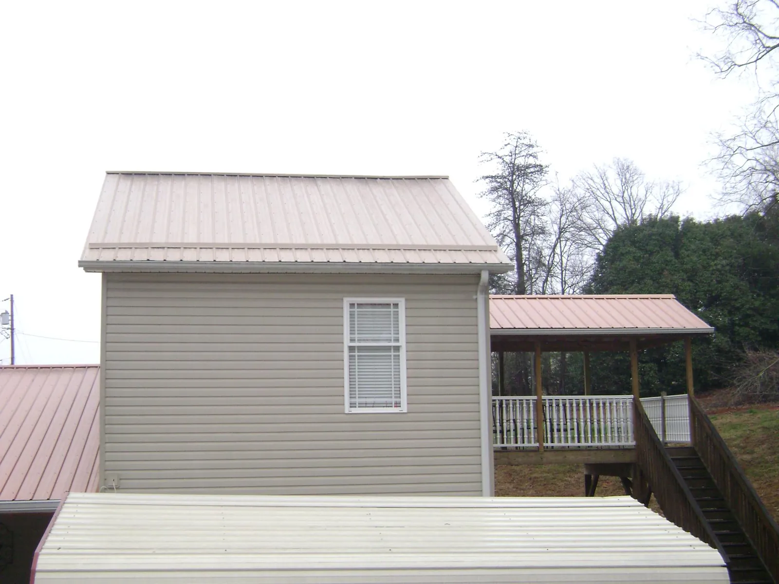 Tan metal roofs on a two story addition and attached porch, from a Roof Replacement job in Oak Lawn