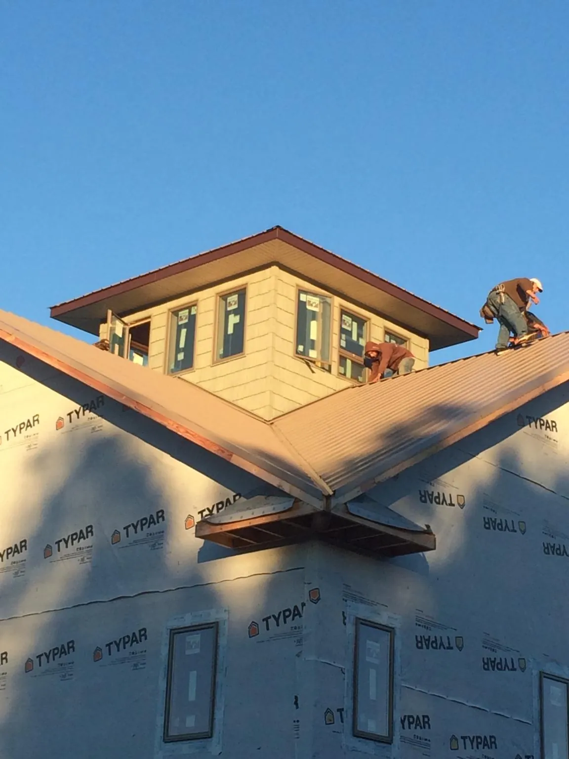 Roofers working around a rooftop cupola on a new metal roof at sunset — Roof Waterproofing in Oak Lawn by Roofing Brothers